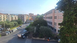Vista da rua com carros estacionados, uma faixa de pedestres e edifícios altos.