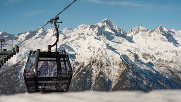 A cable car ascending a snow-covered mountain with a clear sky.