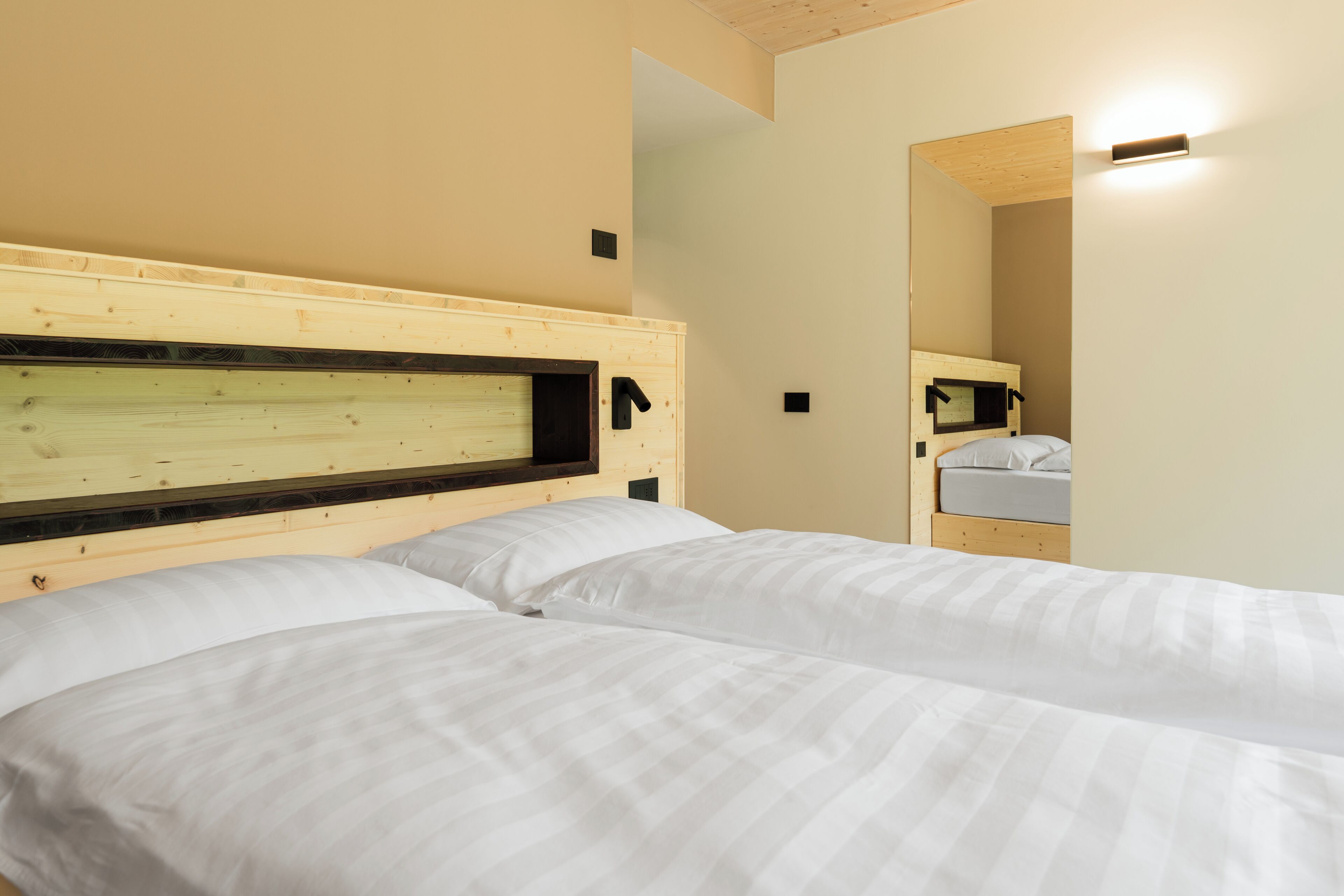 Una habitación de hotel con dos camas, cabeceros de madera y un espejo en la pared.