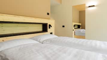 Una habitación de hotel con dos camas, cabeceros de madera y un espejo en la pared.