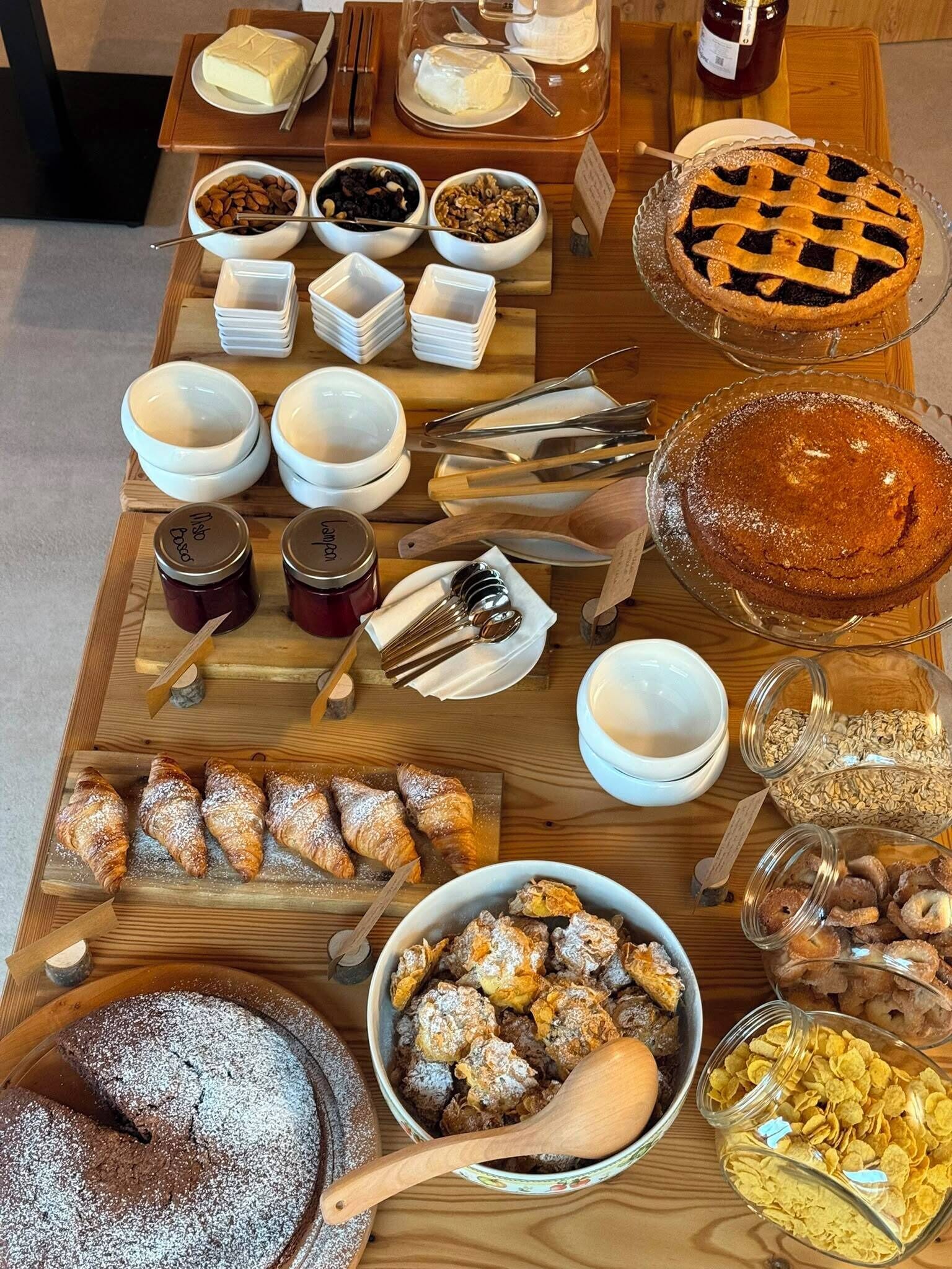 Diversa variedad de postres y pasteles sobre una mesa de madera, incluyendo tartas, bizcochos y galletas.
