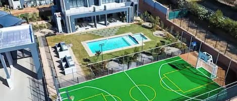 A residential property with a swimming pool and a fenced sports court.