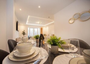A dining area with a table set for four, including plates, glasses, and a bottle. - 157 Vansittart Road (Leeds)