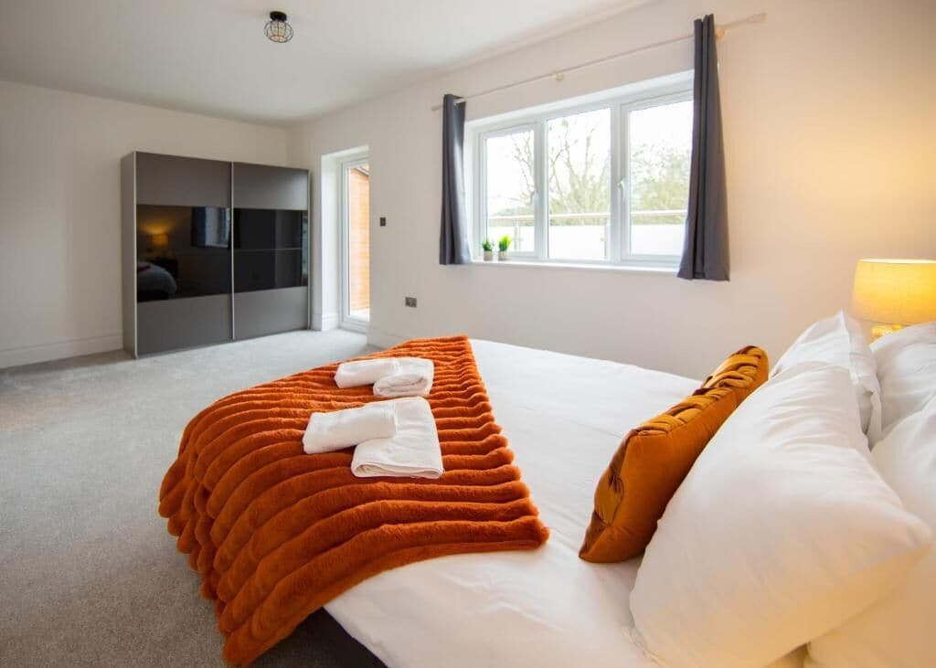 Une chambre d’hôtel avec un lit, une fenêtre avec des rideaux, une armoire et une lampe.