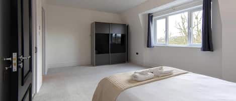 A bedroom with a bed, a wardrobe, a window, and a door.