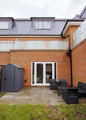 A residential property with a brick exterior, a covered patio area with outdoor furniture, and a sliding glass door leading to an interior space. - 157 Vansittart Road (Leeds)