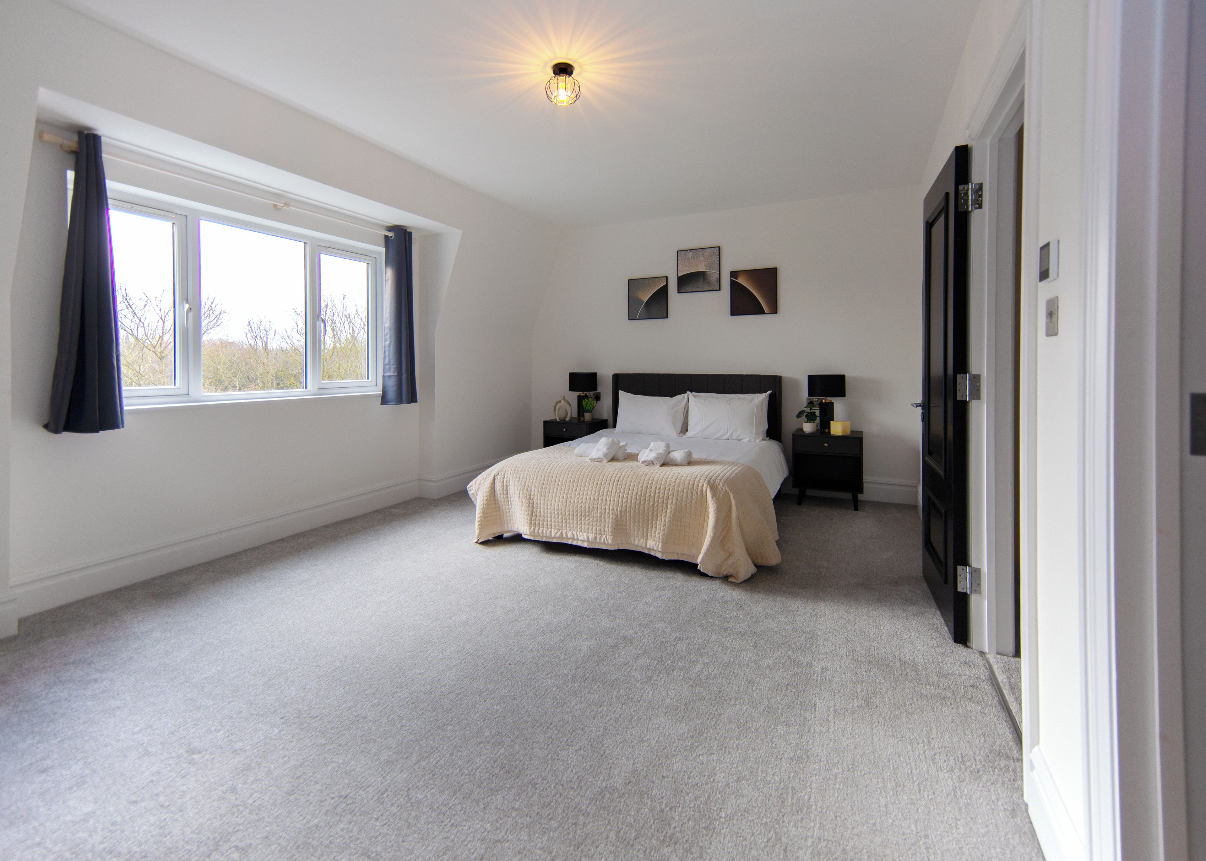 A bedroom with a bed, bedside tables, a window, and a door.