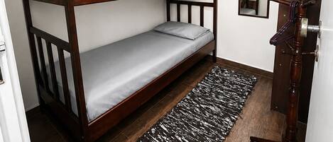 A room with a bunk bed, a mirror, a coat rack, and a patterned rug.