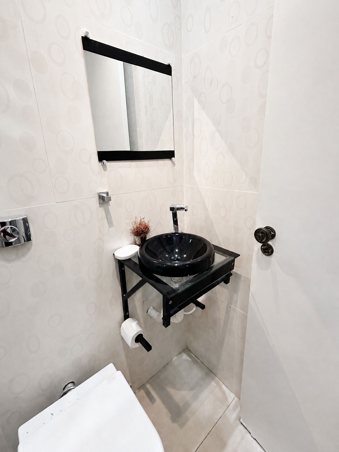 A compact bathroom with a black sink, a toilet, and a mirror.