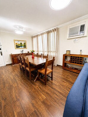 A dining area with a wooden table and chairs, a vase with flowers, and a painting on the wall. - Cove retreat with 4 bedrooms, pool and comfort. (Guarujá)