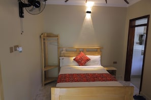 A bedroom with a bed, a wooden headboard, a bedside table, a hanging fan, and a light fixture.