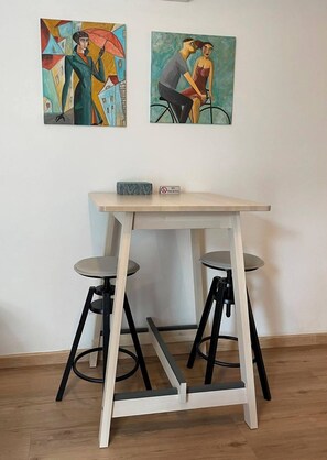 Ein Tisch mit zwei Hocker, ein 'NICHTRAUCHERN'-Schild und zwei abstrakte Gemälde an der Wand.