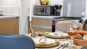Uma sala de jantar com uma mesa posta para dois, um micro-ondas e um fogão ao fundo.
