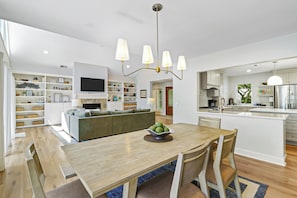 A modern kitchen with a dining area, built-in shelving, and a TV. - Sunset Rentals | Port Tack 67 (Hilton Head Island)