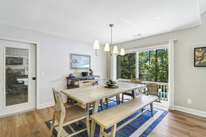 A dining area with a wooden table, benches, and a chandelier. - Sunset Rentals | Port Tack 67 (Hilton Head Island)