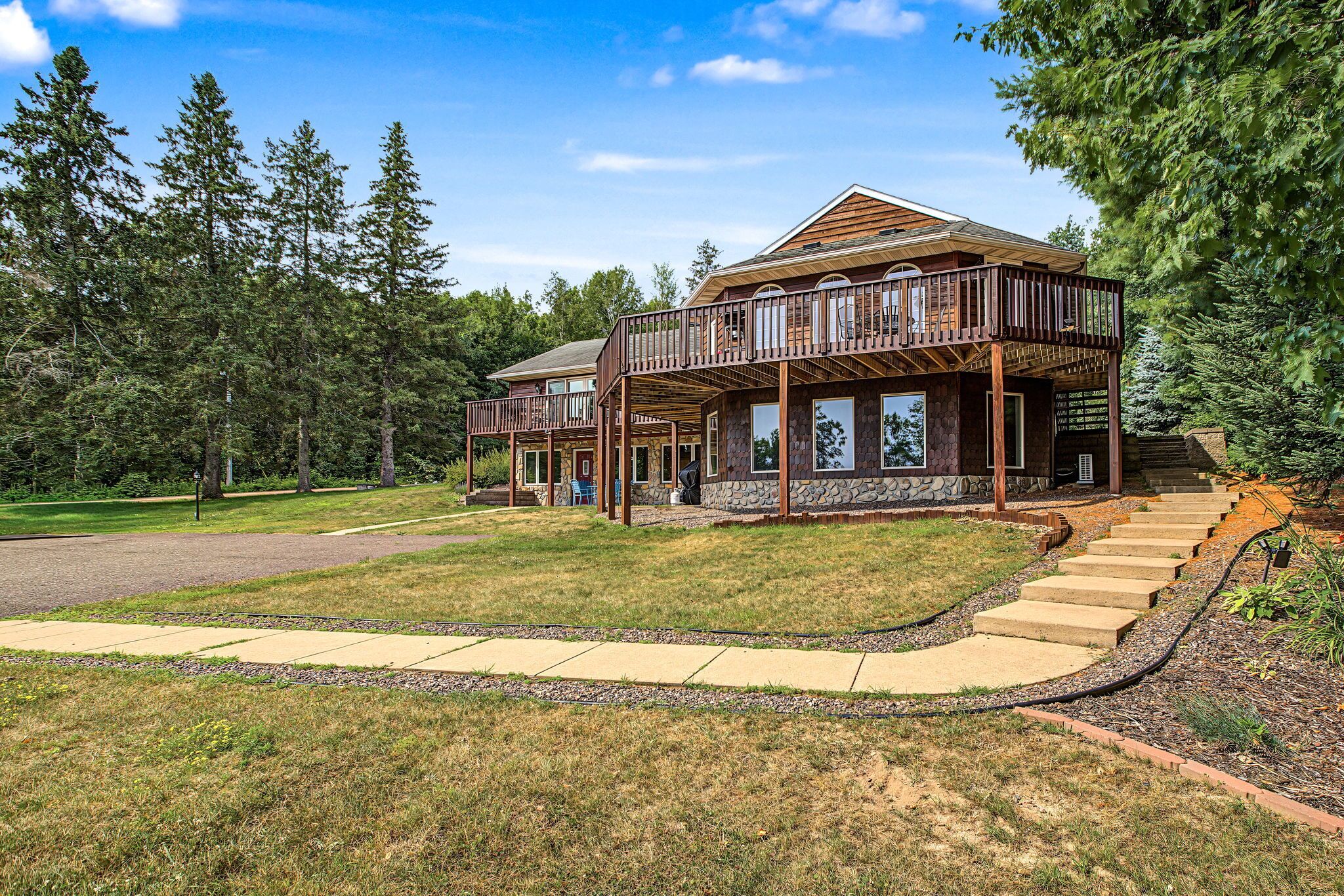 A two-story house with a deck and a stone foundation.