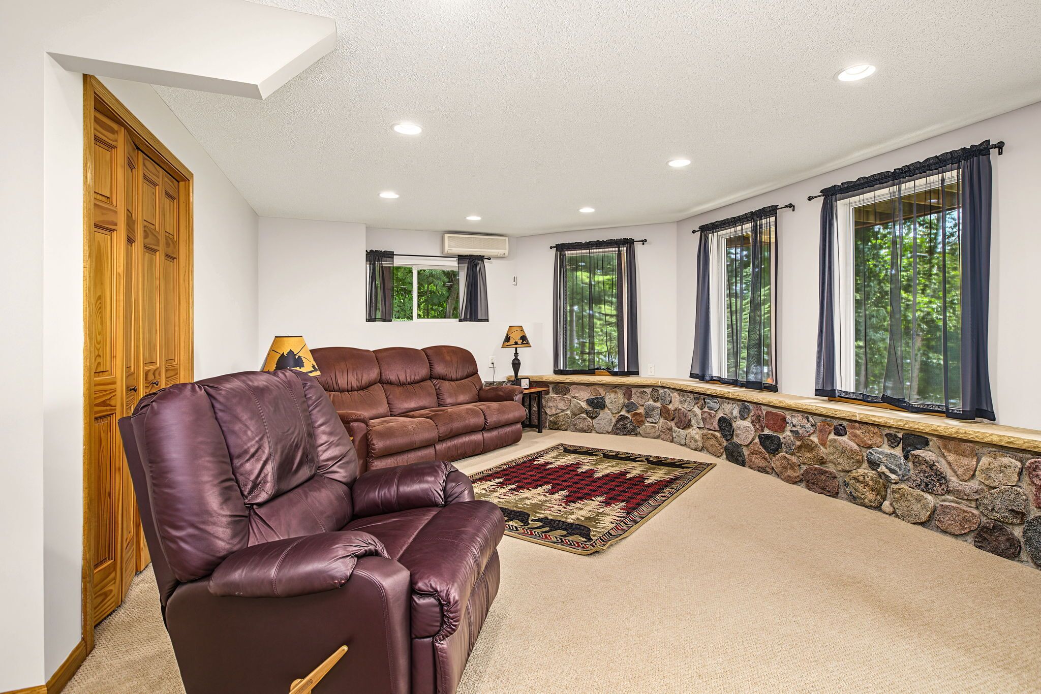 A living room with a leather sofa, a rug, and a stone wall.