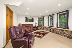 A living room with a leather sofa, a rug, and a stone wall.