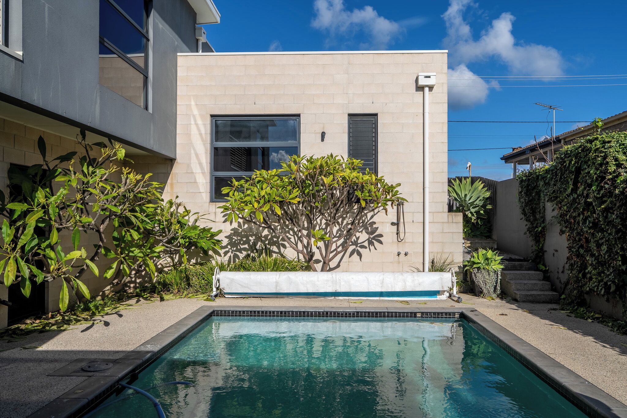 A swimming pool with a tiled edge, surrounded by a concrete deck.