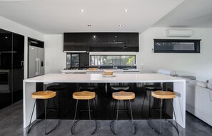 A modern kitchen with a central island, bar stools, and a large window.