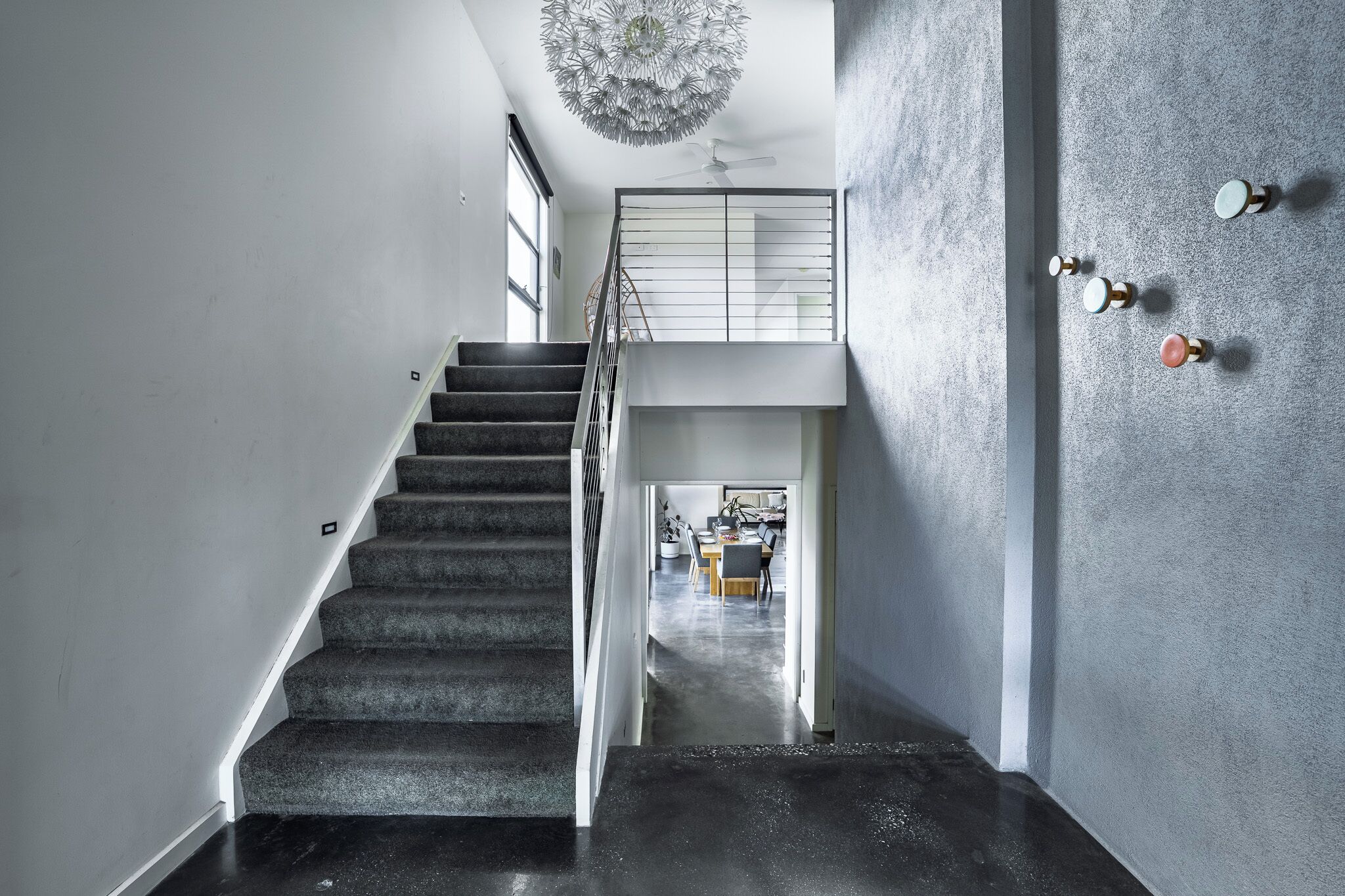 Eine Treppe führt zu einer erhöhten Ebene, im Hintergrund sind ein Esstisch und Stühle zu sehen.