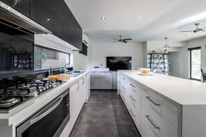 Eine moderne Küche mit Kochinsel, integrierten Geräten und einem großen Fenster.