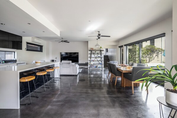 A modern kitchen with a bar area, dining space, and a ceiling fan.