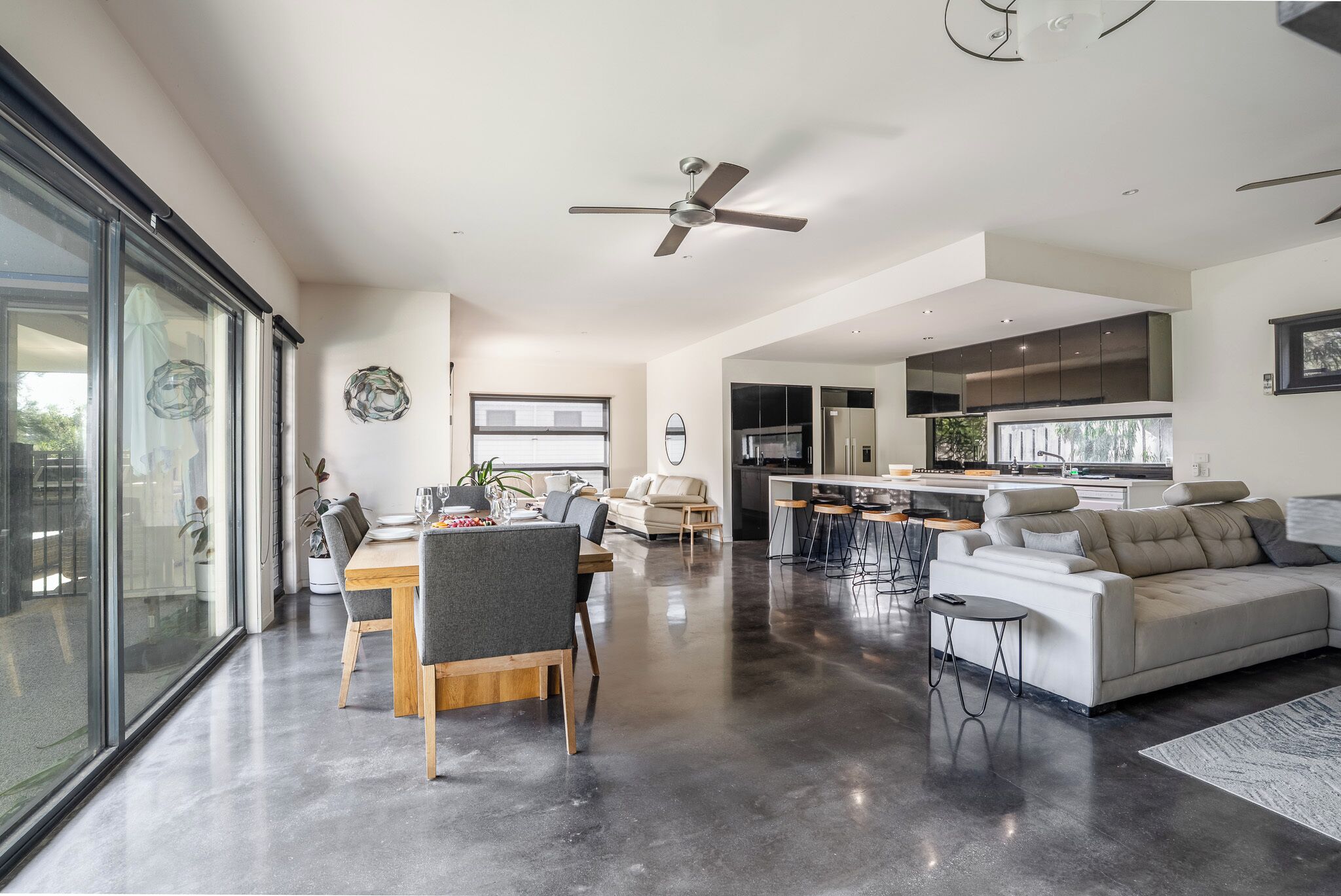 A spacious living area with a dining table, sofas, and a kitchen area.