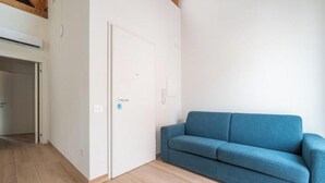 A room with a blue sofa, a white door, and a wooden floor. - Estay - Lovely Marina Roof (Cagliari)