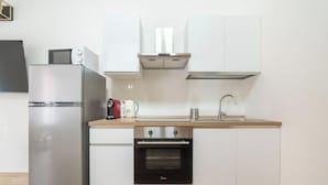 A compact kitchen with a stainless steel refrigerator, a built-in oven, a microwave, and a sink with a faucet. - Estay - Lovely Marina Roof (Cagliari)
