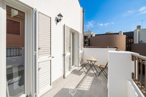 A balcony with a table and chairs, a sliding door, and a small outdoor seating area. - Estay - Lovely Marina Roof (Cagliari)