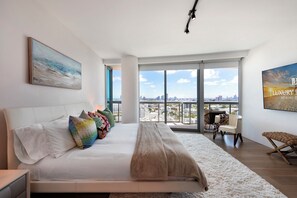 A modern bedroom with a large bed, colorful pillows, a view of the city, and a balcony. - Ocean View Private Residence at The Setai - 3006 (Miami Beach)