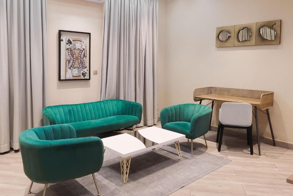 Una sala de estar moderna con un sofá turquesa, una mesa de centro blanca y un escritorio de madera.