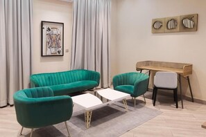 Un saló modern amb un sofà color turquesa, una taula de café blanca i un escriptori de fusta.