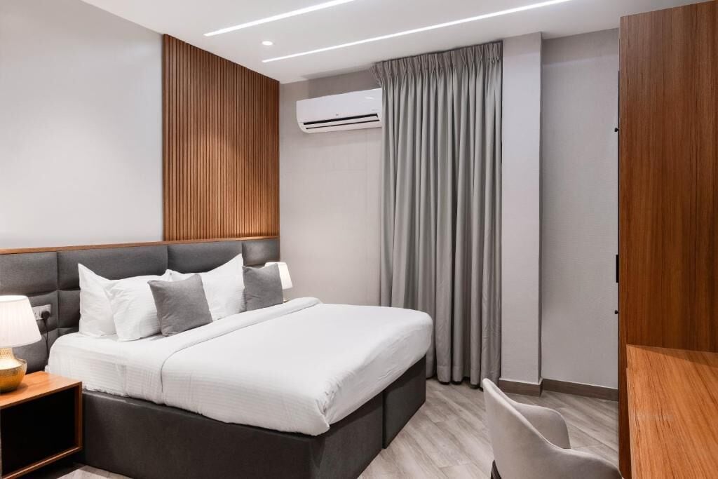 Une chambre d’hôtel moderne équipée d’un lit, d’une table de chevet, d’une lampe, d’un climatiseur et de rideaux.