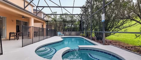 Una piscina de diseño curvo, rodeada por un porche cubierto con asientos y vistas a un paisaje verde.