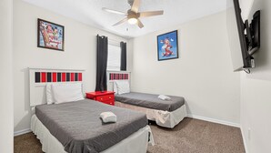 Ein Schlafzimmer mit zwei Betten, einem Deckenventilator und zwei an der Wand befestigten Fernsehern.