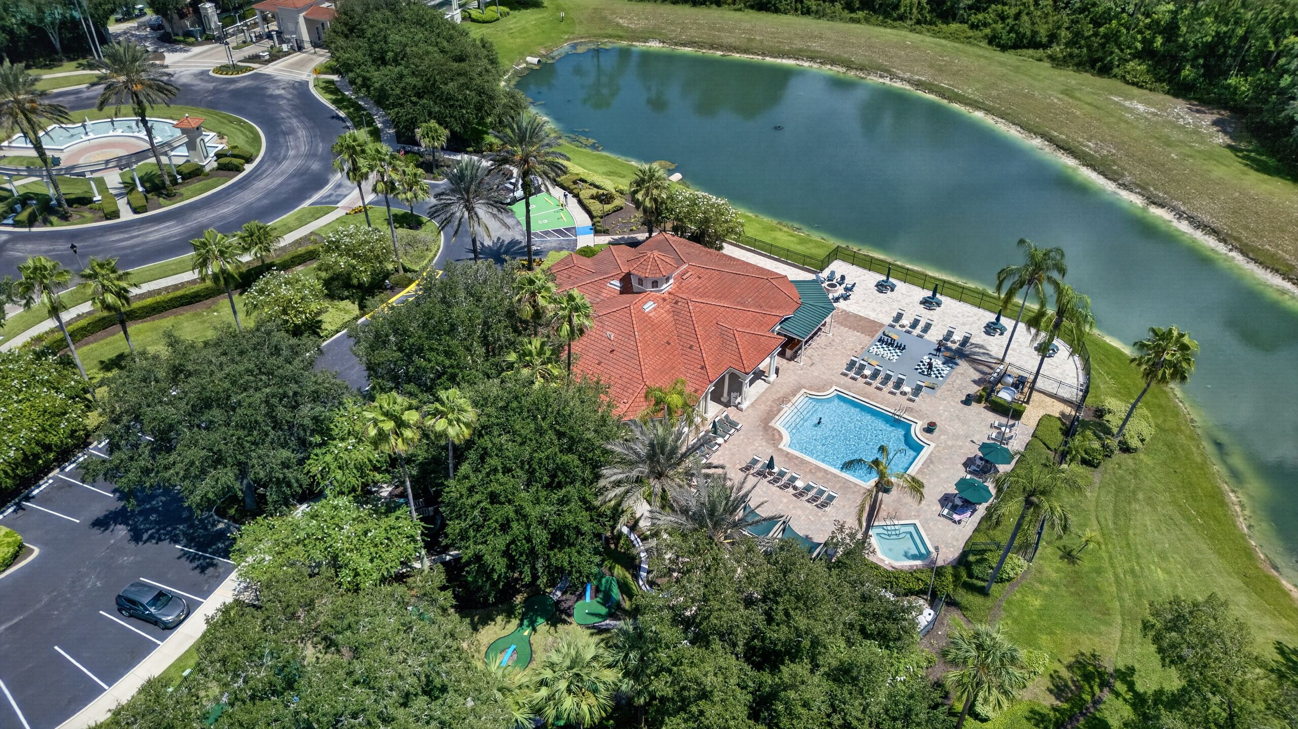 A resort with a swimming pool, lounge chairs, and a tennis court.