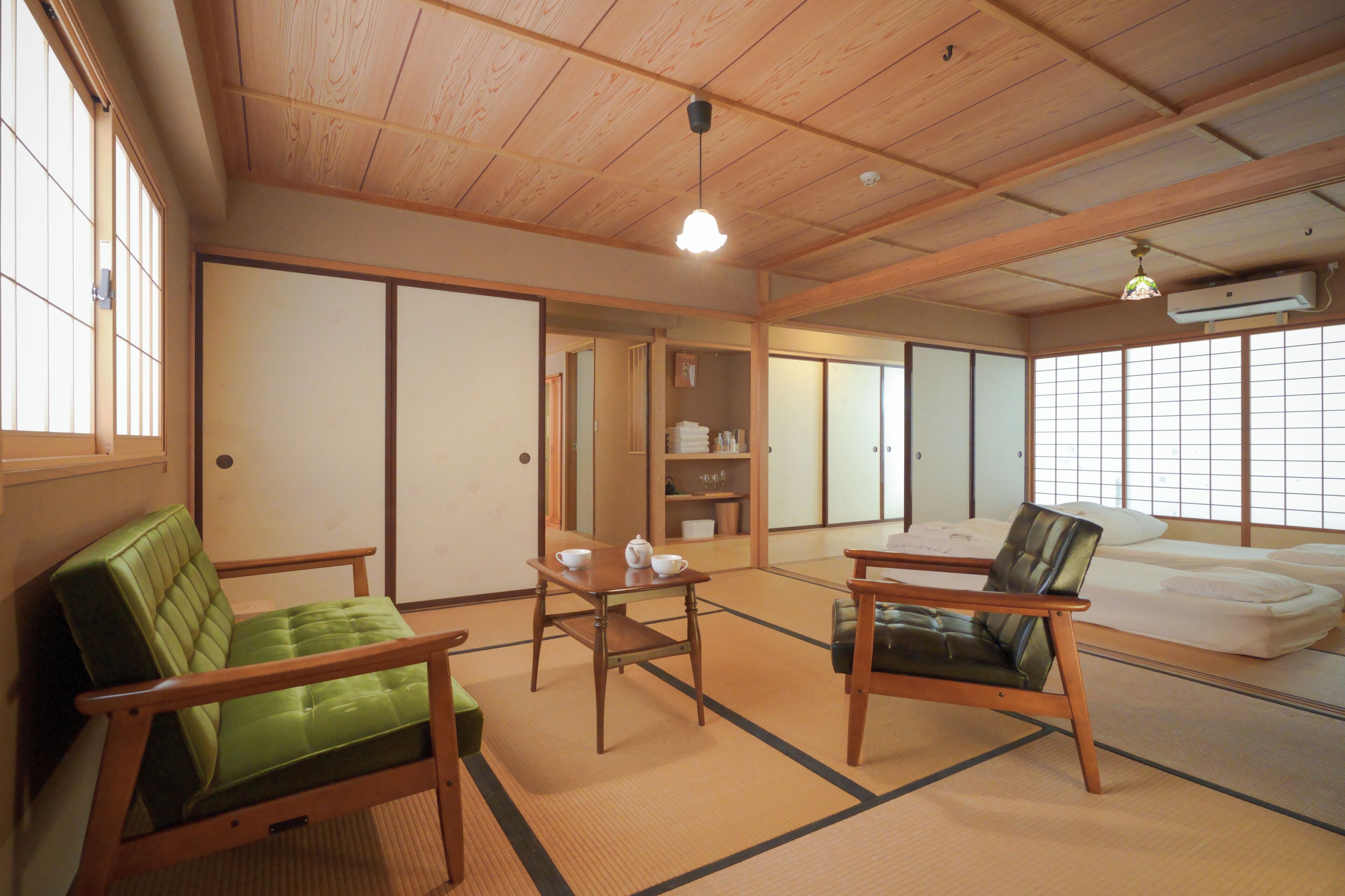 A traditional Japanese room with tatami flooring, a low wooden ceiling, and sliding doors.