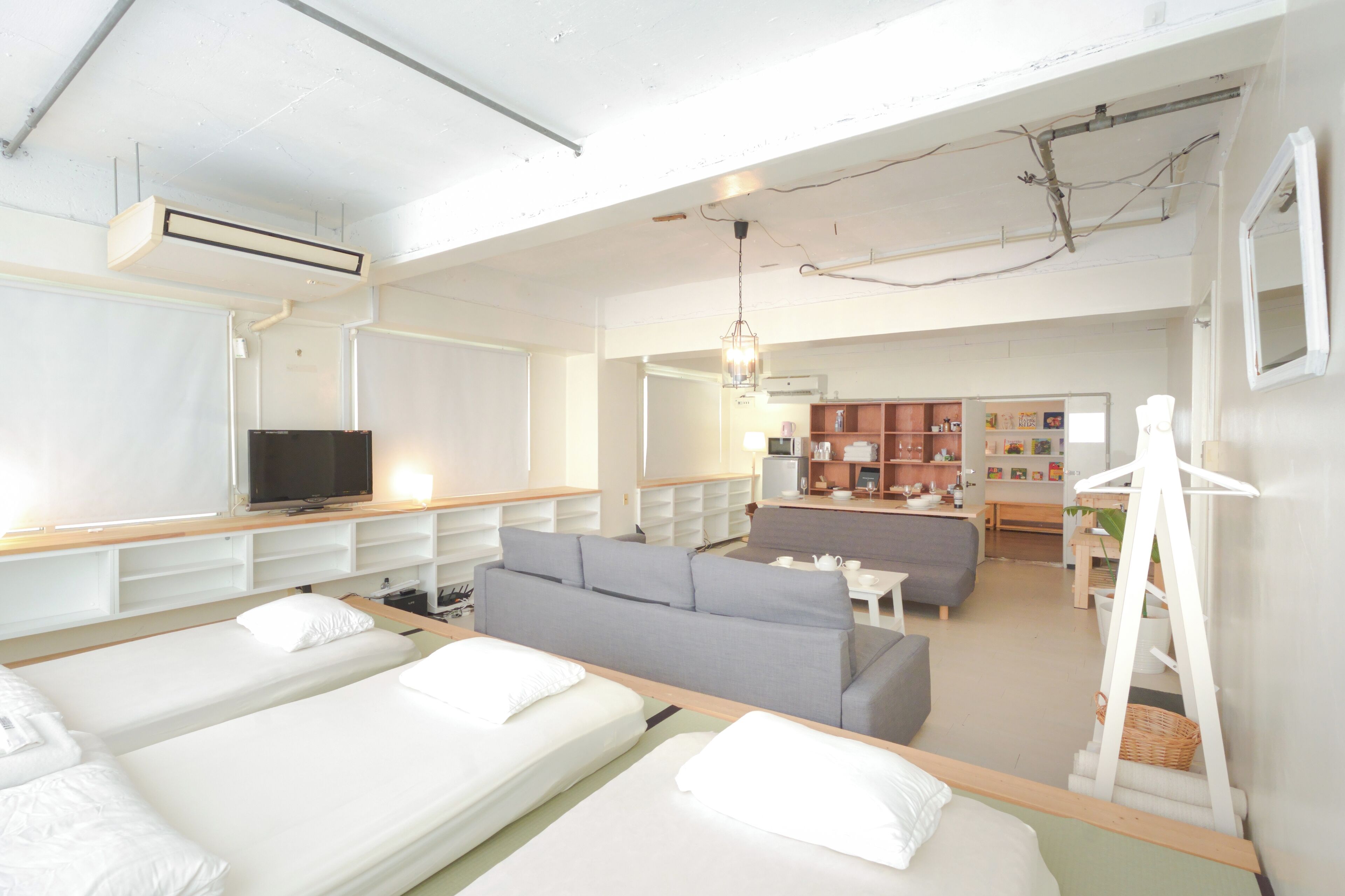 A hotel room with two beds, a sofa, a dining area, and a kitchenette.