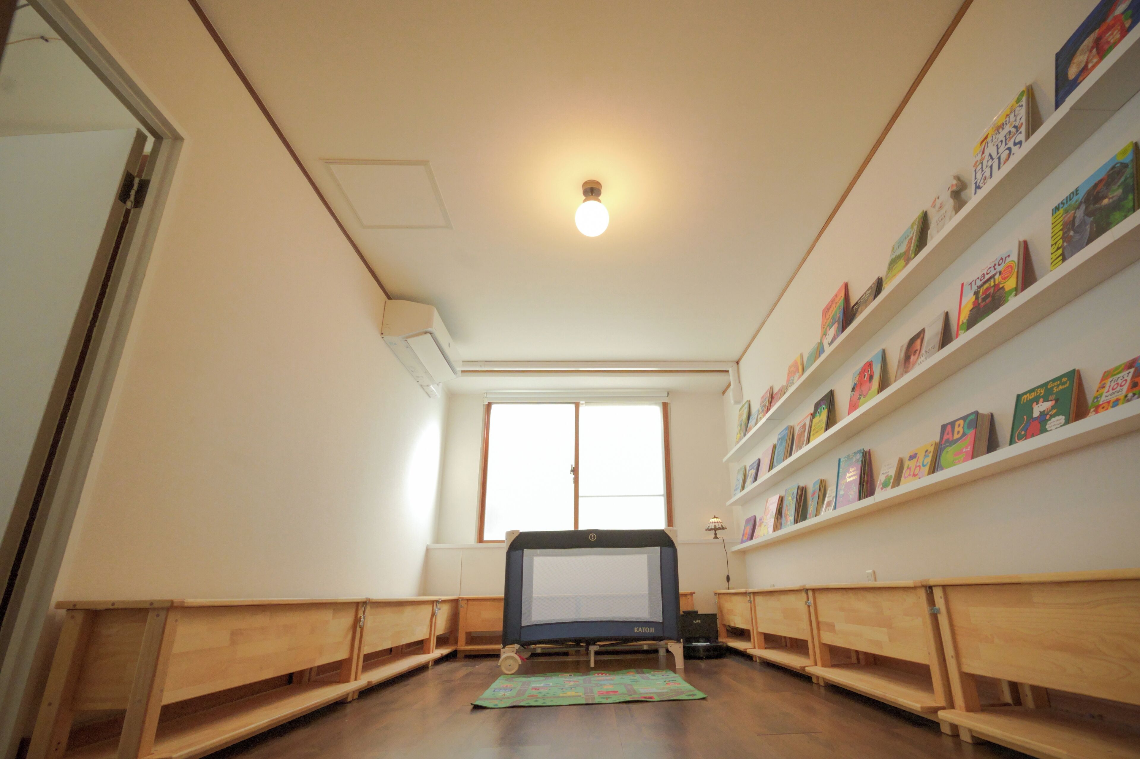 A room with a television, wooden benches, and bookshelves with children's books.