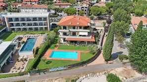 A residential building with a swimming pool, multiple balconies, and a paved driveway. - Casa Matilda in Sirmione (Sirmione)