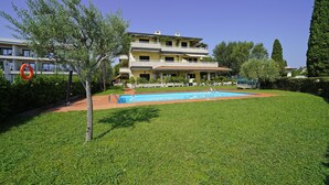 A two-story building with a swimming pool, surrounded by well-maintained grass and trees. - Casa Matilda in Sirmione (Sirmione)
