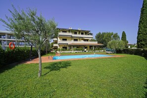 A two-story building with a swimming pool, surrounded by well-maintained grass and trees. - Casa Matilda in Sirmione (Sirmione)