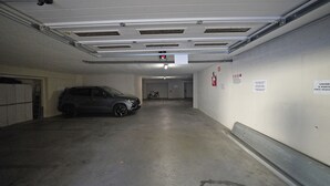 A parking garage with a car parked in a space, concrete walls, and a ceiling with ventilation. - Casa Matilda in Sirmione (Sirmione)