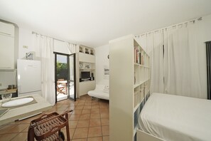 A compact room with a kitchenette, a dining area with a table and chairs, a bed, and a bookshelf. - Casa Matilda in Sirmione (Sirmione)