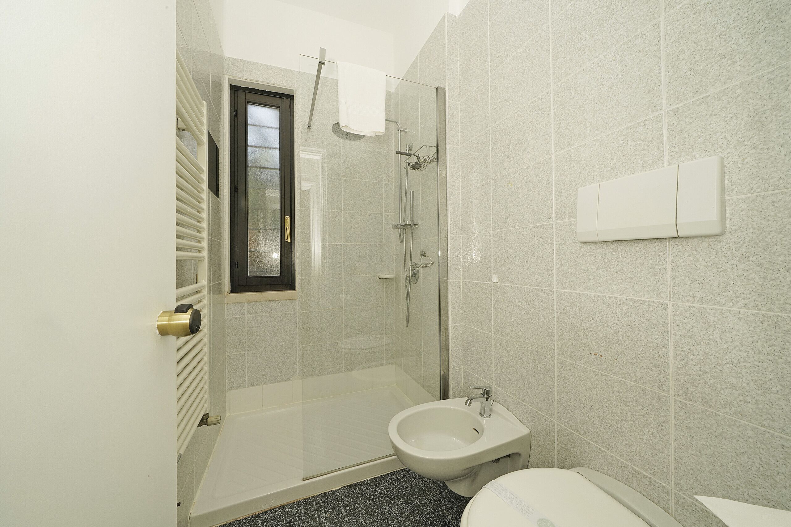 A bathroom with a shower, bidet, and toilet.