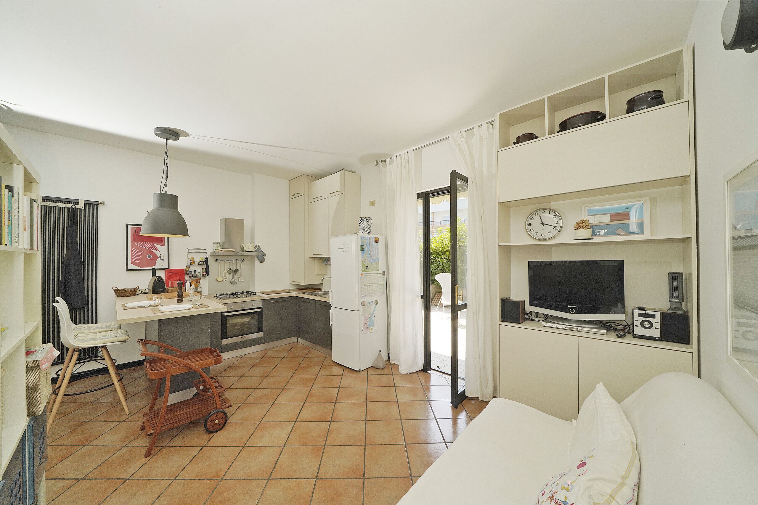 A compact living space with a kitchenette, a dining area, and a seating area with a television and audio equipment.
