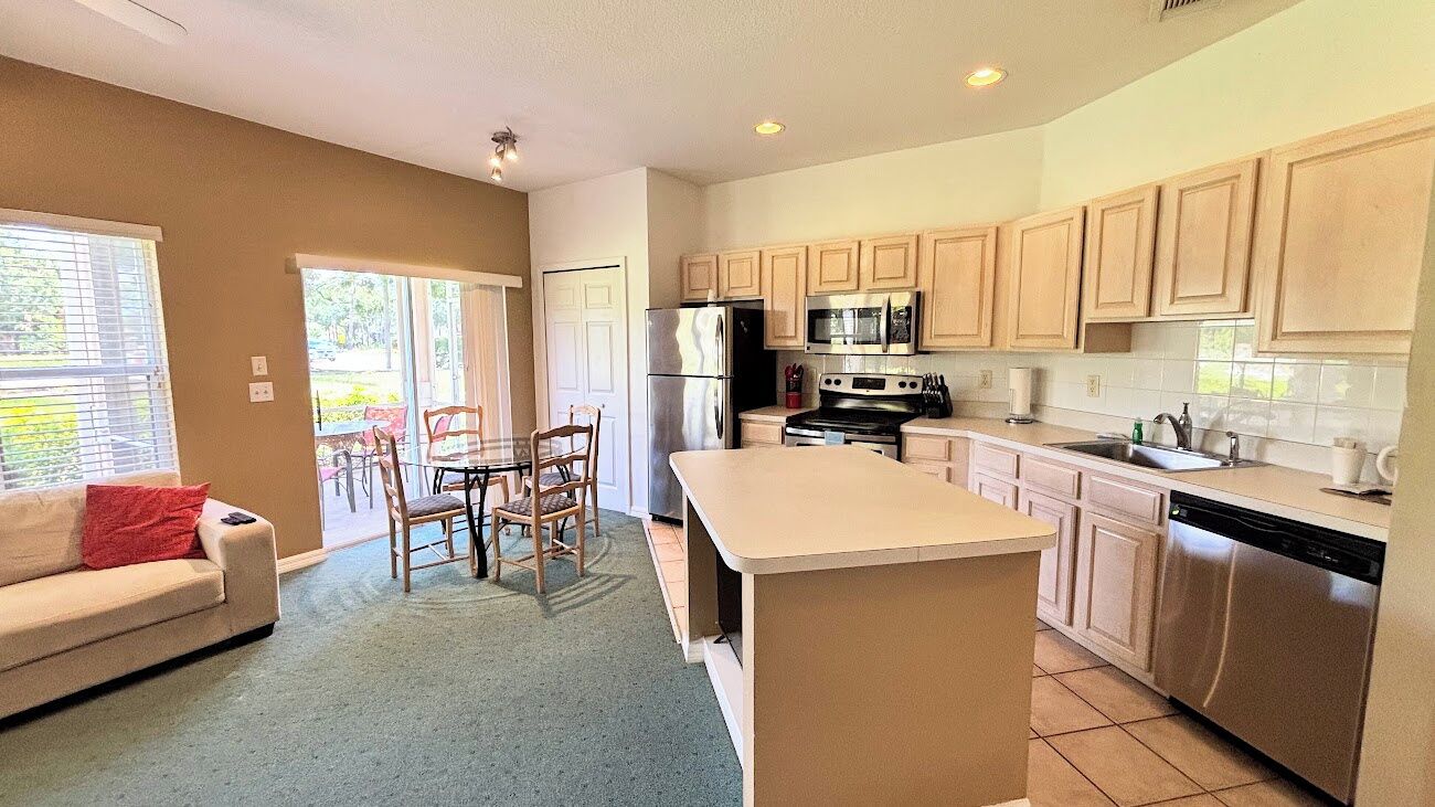 A modern kitchen with a central island, stainless steel appliances, and wooden cabinets.