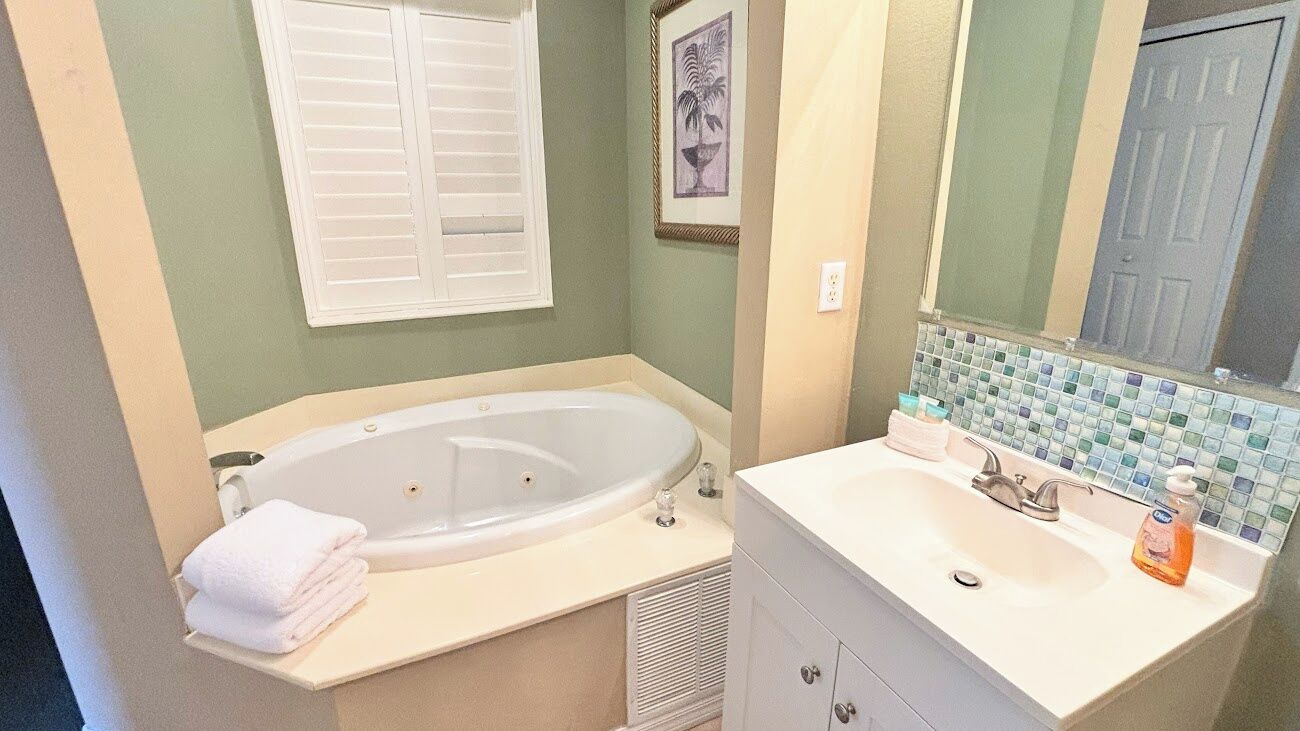 Un baño con bañera, lavamanos y espejo.